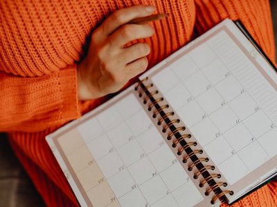 Person, welche einen Kalender und Bleistift in der Hand hält