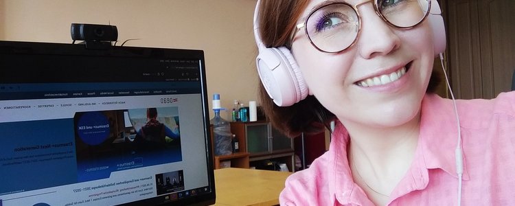 Eine Frau mit Kopfhörern sitzt vor einem PC
