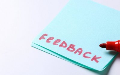 Das Wort Feedback steht in roter Schrift auf einem blauen Postit
