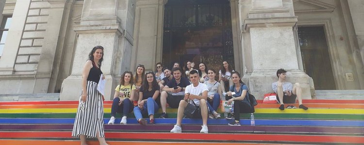 Junge Menschen sitzen auf den bunt bemalten Stufen der Universität Wien. Links OeAD-Lektorin Martina Drescher