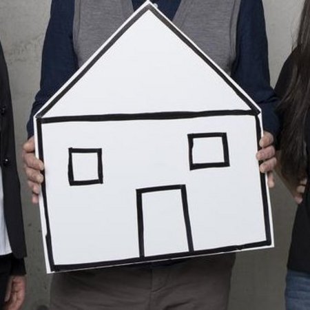 Vier Personen mit einem Haus aus Karton