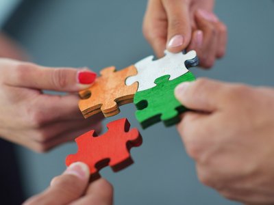 Puzzlestücke, die von vier Händen gehalten und zusammengesetzt werden