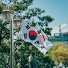 zwei südkoreanische Flaggen vor einem Baum und einem modernen Gebäude