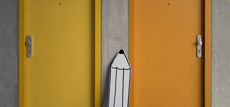 Zwei Türen und ein großer Bleistift aus Karton